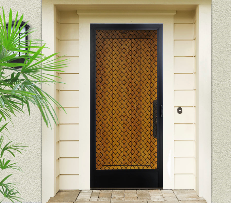 Black security door with diamond mesh over a wooden door, surrounded by beige trim, next to a leafy green plant.
