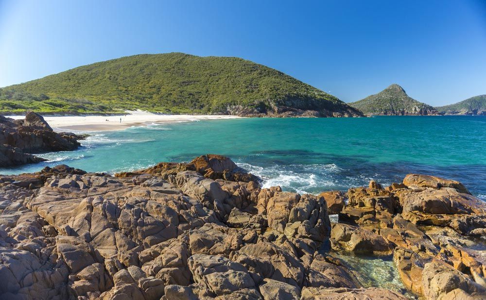 A Rocky Beach With A Mountain In The Background — Prestige Horse Carriages in Central Coast, NSW