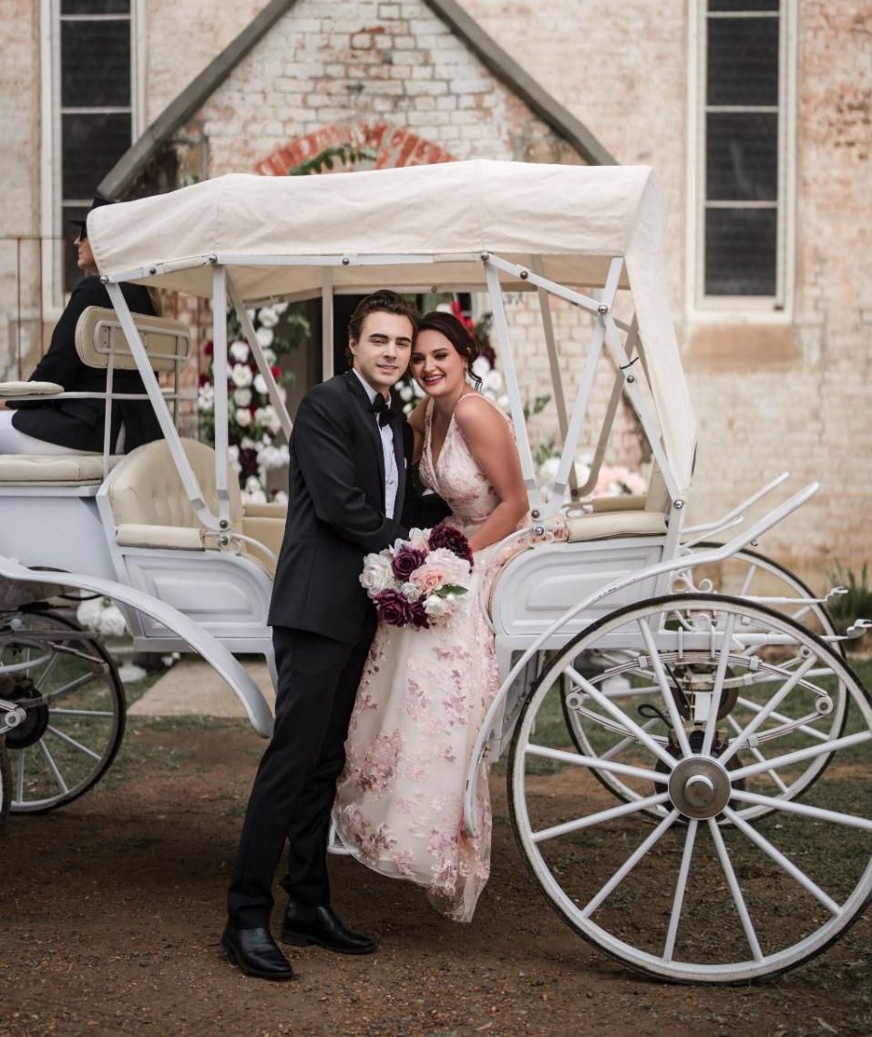 A Bride and Groom Are Posing for a Picture in Front of a Horse Drawn Carriage — Prestige Horse Carriages in Mitchells Flat, NSW