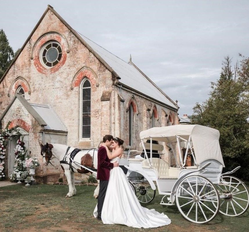 A Bride and Groom Are Kissing in Front of a Horse Drawn Carriage — Prestige Horse Carriages in Mitchells Flat, NSW