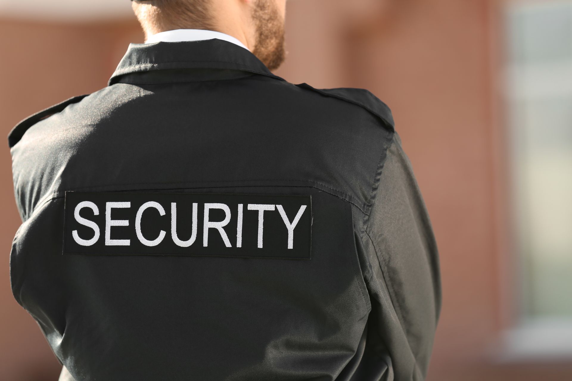 Security guard, back view, wearing a black uniform with 
