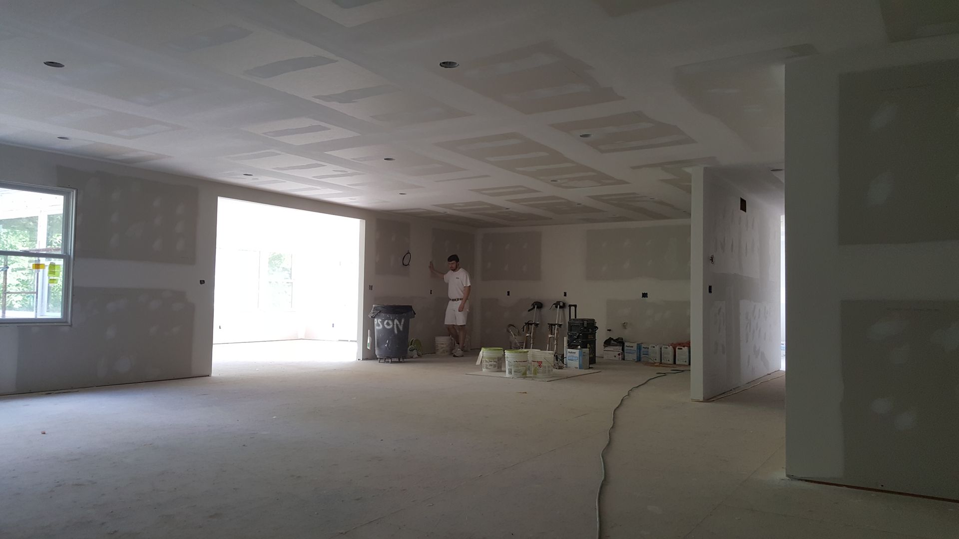 A man in a white shirt is standing in an empty room.