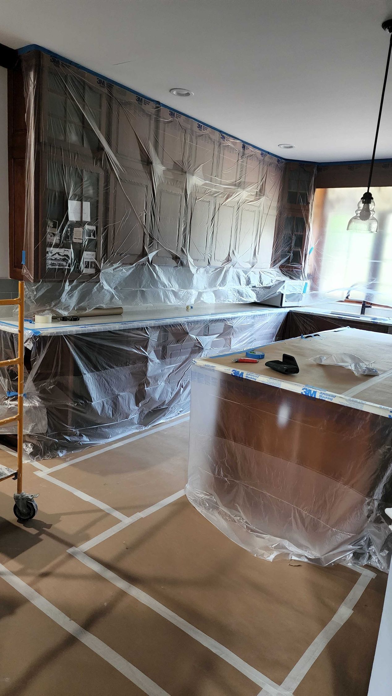 A kitchen is being remodeled and covered in plastic.