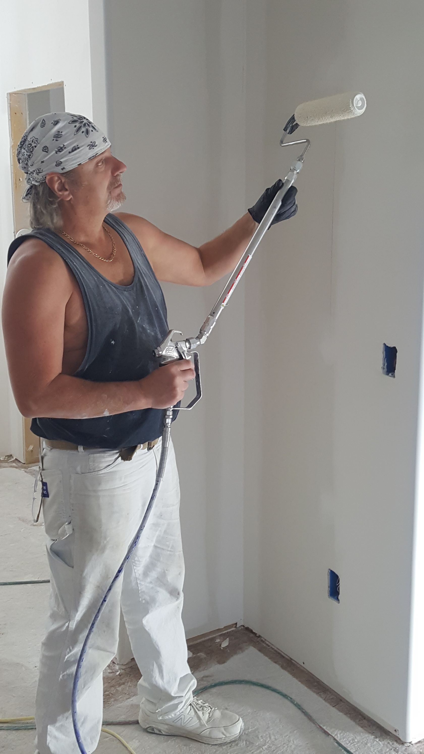 A man is painting a wall with a paint roller.