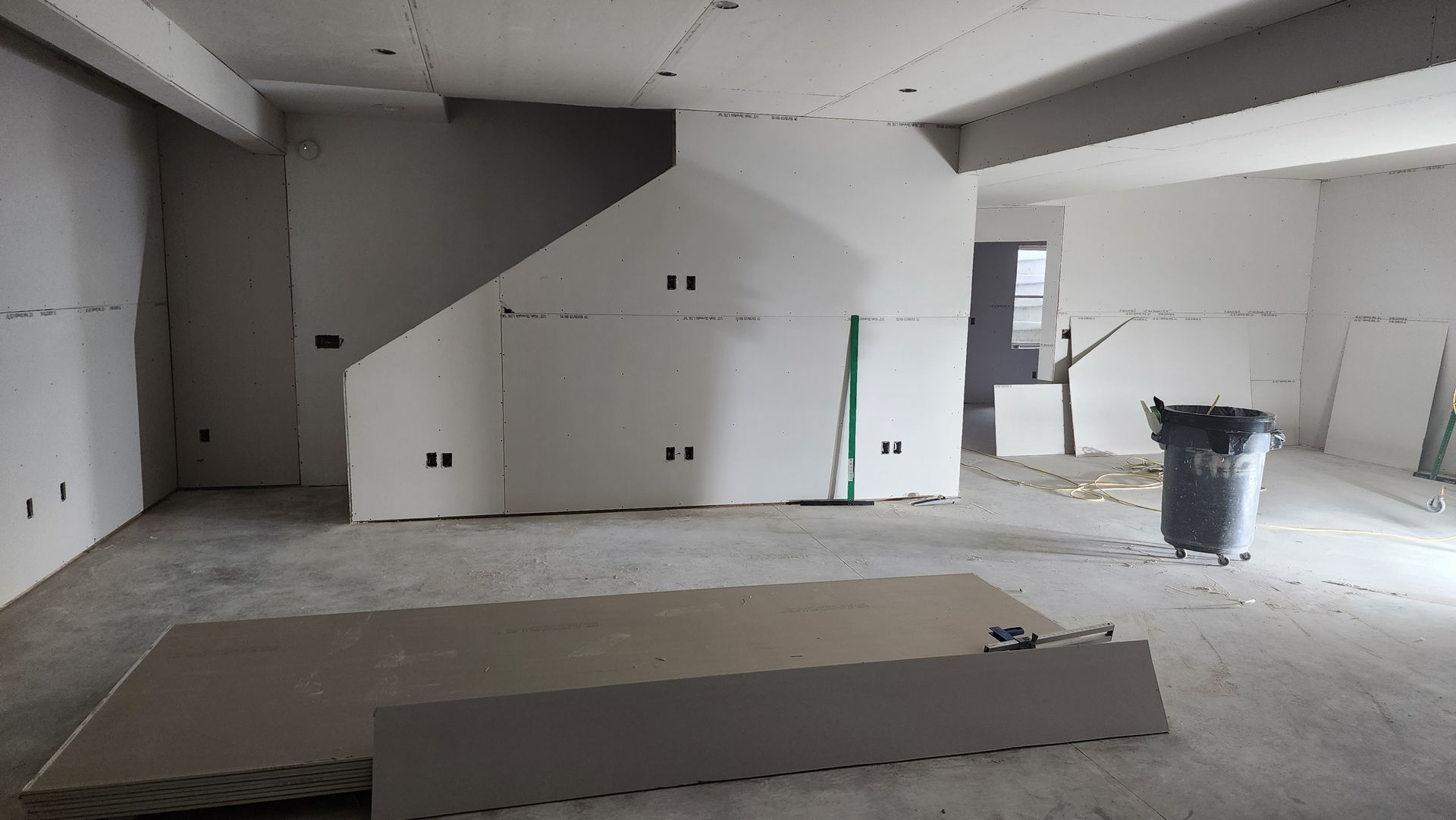 An empty room with a staircase and a trash can