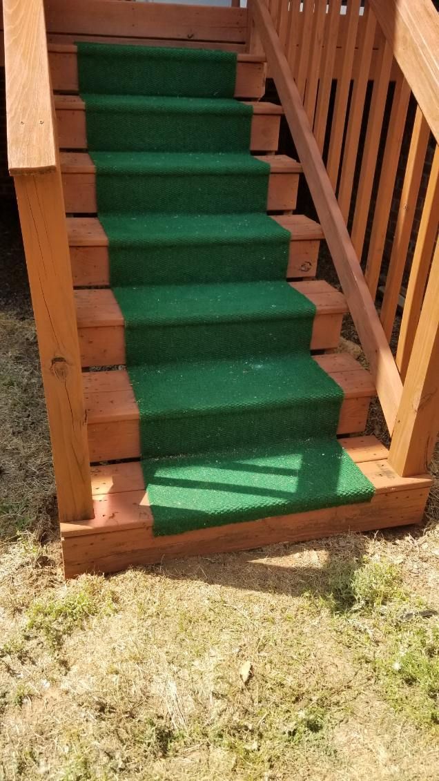 Wooden outdoor staircase with green carpet runner.