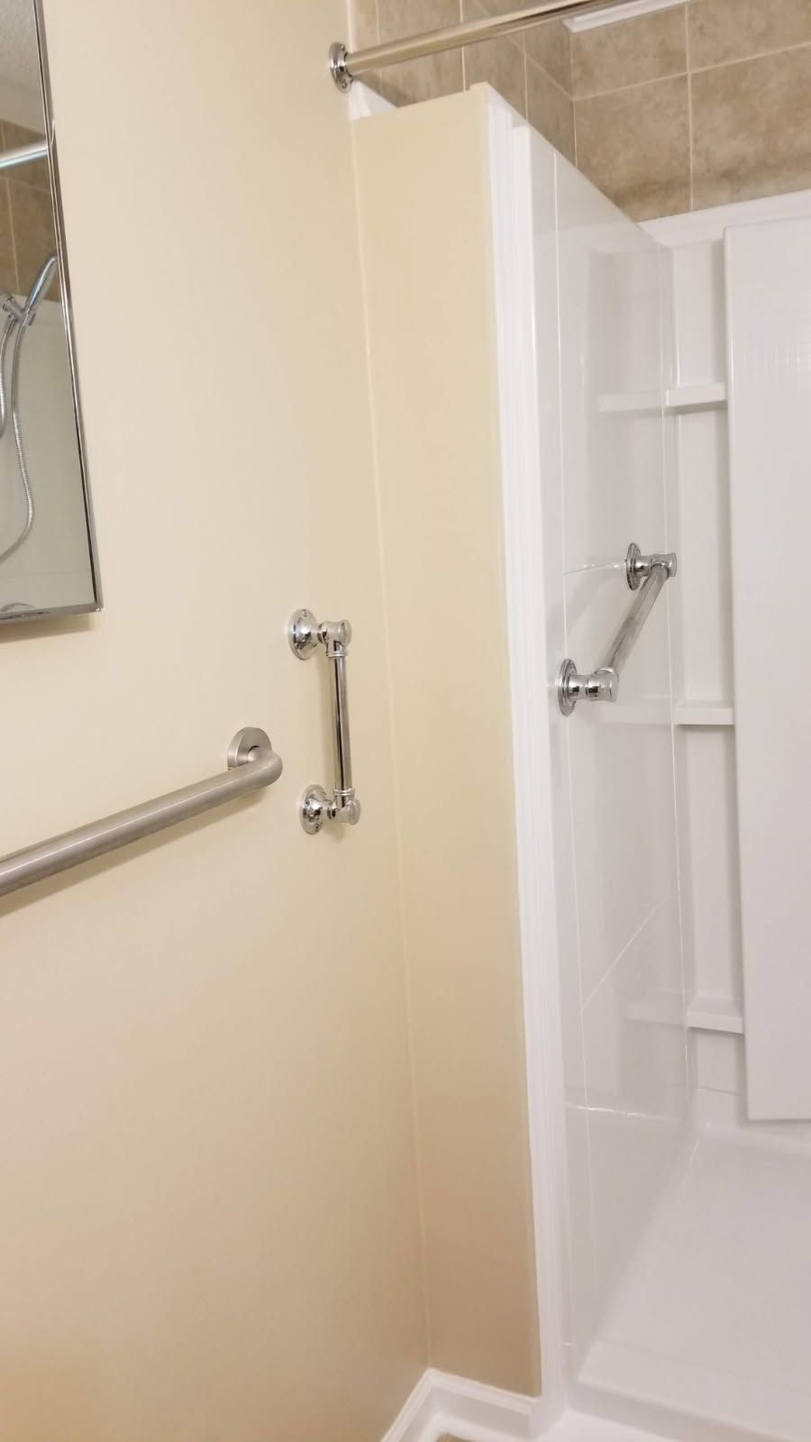 Bathroom with grab bars: tub/shower, wall-mounted handrail, and chrome handles for accessibility.