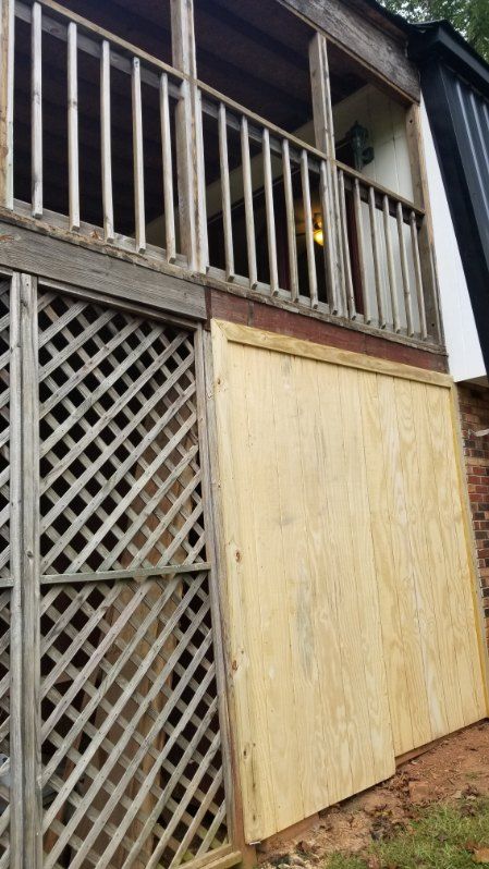 Wooden house exterior with a deck, lattice, and plywood siding.