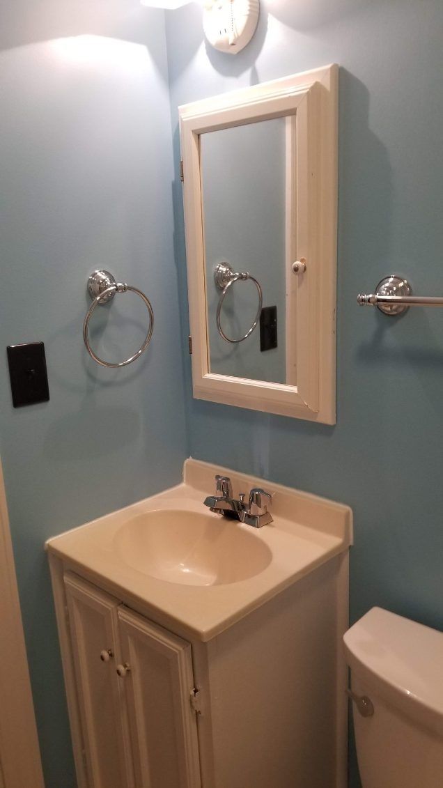 Bathroom with blue walls, white vanity, and mirror above the sink. Chrome towel rack and ring.