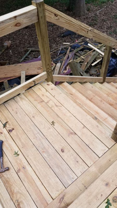 Wooden deck with stairs under construction.  Railings are present.  Scrap wood debris is in the background.