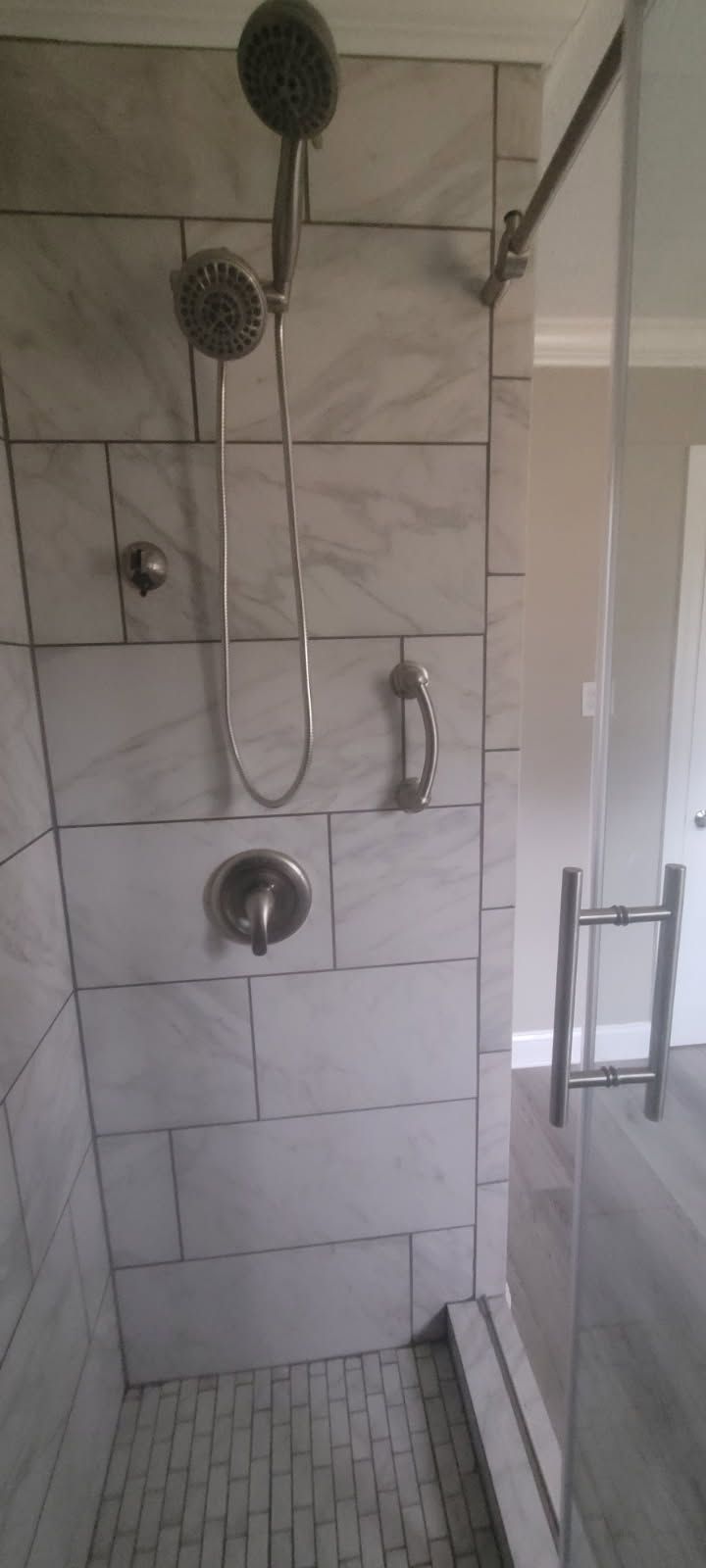 Shower with tile walls, a glass door, and a multi-head shower fixture.