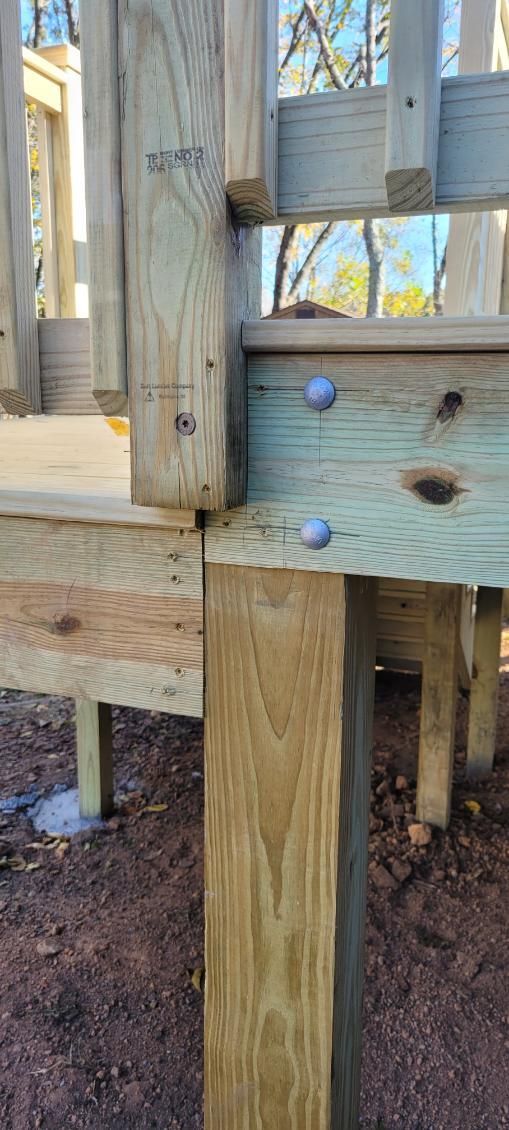Wooden deck construction with a corner post and supporting beams.