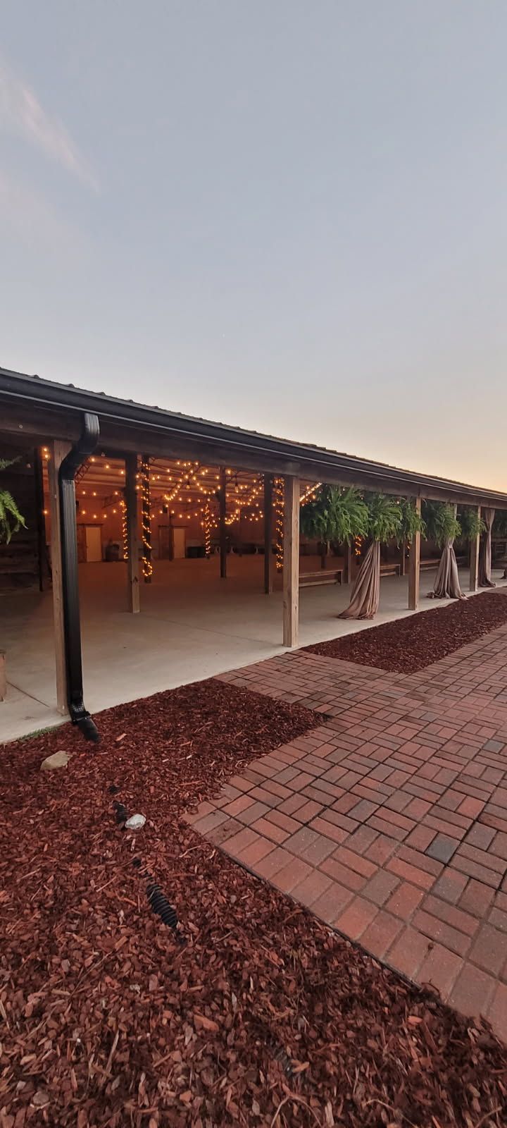 Outdoor event space with string lights, brick pavers, and mulch.