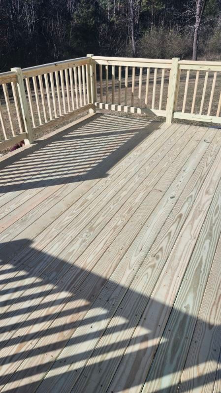 Wooden deck with railings, casting long shadows. Sunlight highlights the natural wood grain and construction.