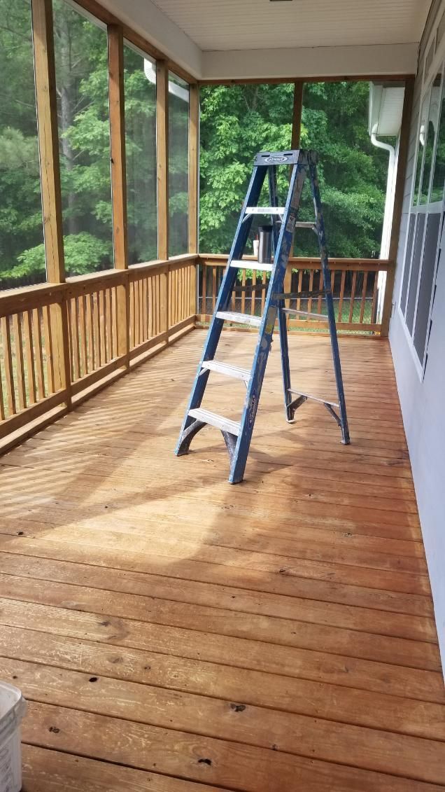 Blue ladder on a wooden deck with railing; forest visible in the background.