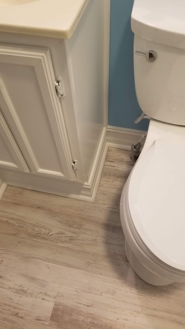 Bathroom with a white toilet, cabinet, and light-colored flooring.