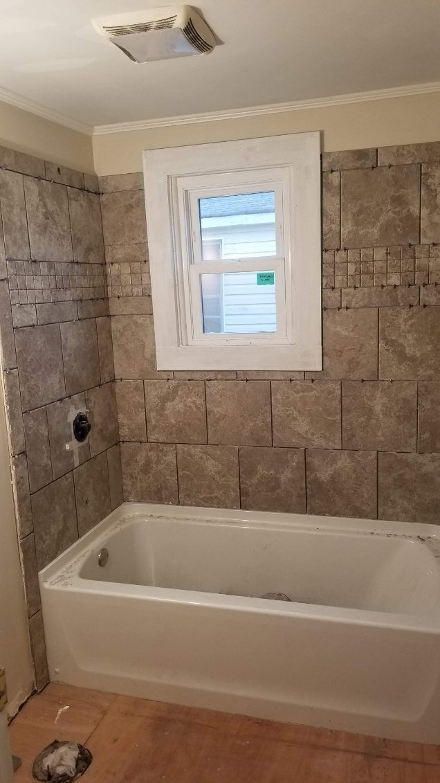 Bathroom with a bathtub, tiled walls, and a window.