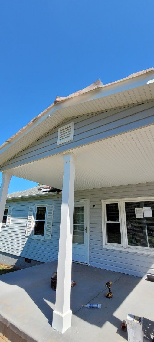 A light blue house with a porch and white pillars under a clear blue sky.