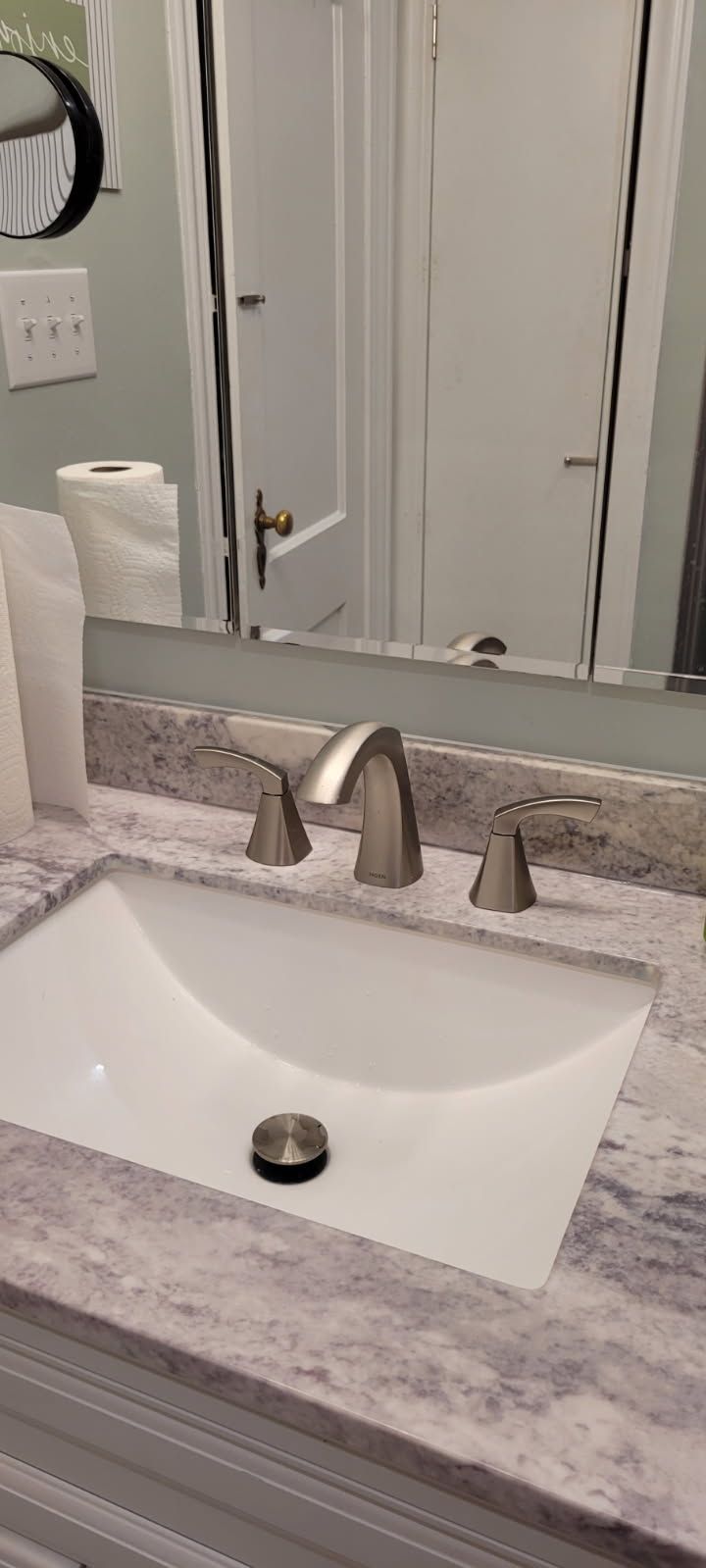 Bathroom sink with faucet and light gray countertop; reflection in mirror.