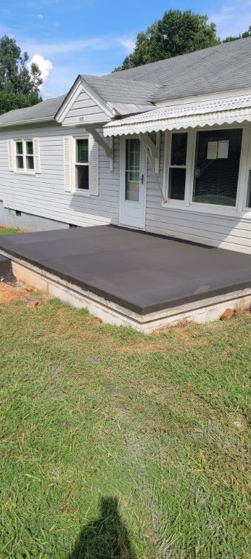 A white house with a dark patio, green grass, and a blue sky.