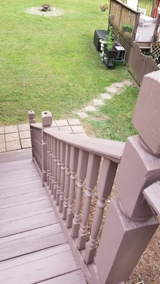 Staircase leading down to a grassy yard, with a wooden railing and a stone walkway.