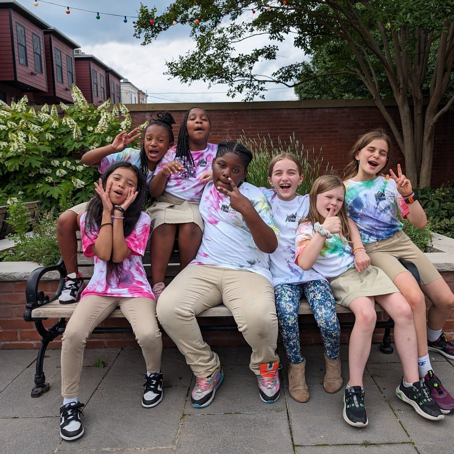 A group of young girls are posing for a picture while sitting on a bench.