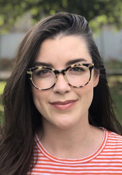 A woman wearing glasses and a striped shirt is smiling for the camera.