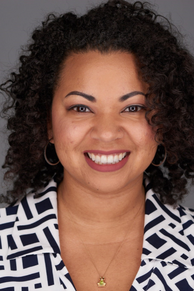 A woman with curly hair is smiling for the camera