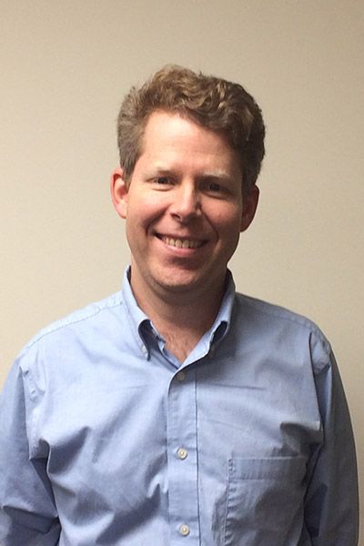 A man in a blue shirt is smiling for the camera