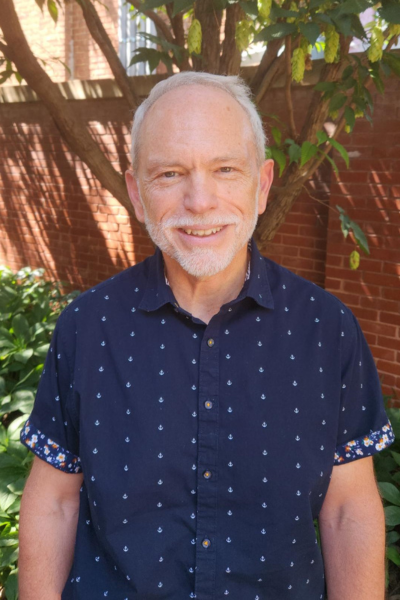 A man with a beard is wearing a blue shirt with white polka dots.