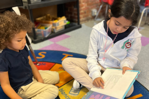 A boy and a girl are sitting on the floor reading books.