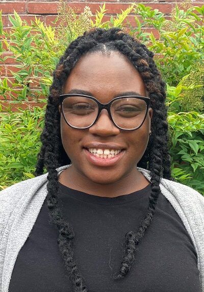 A woman wearing glasses and a black shirt is smiling for the camera.