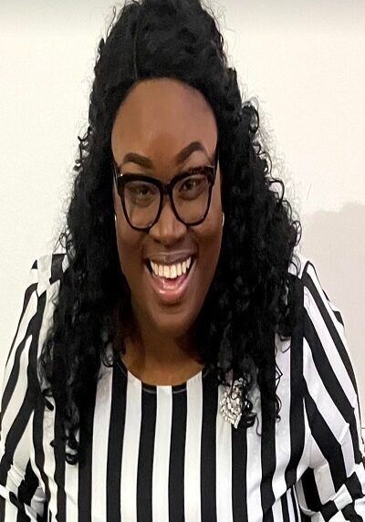A woman wearing glasses and a black and white striped shirt is smiling.