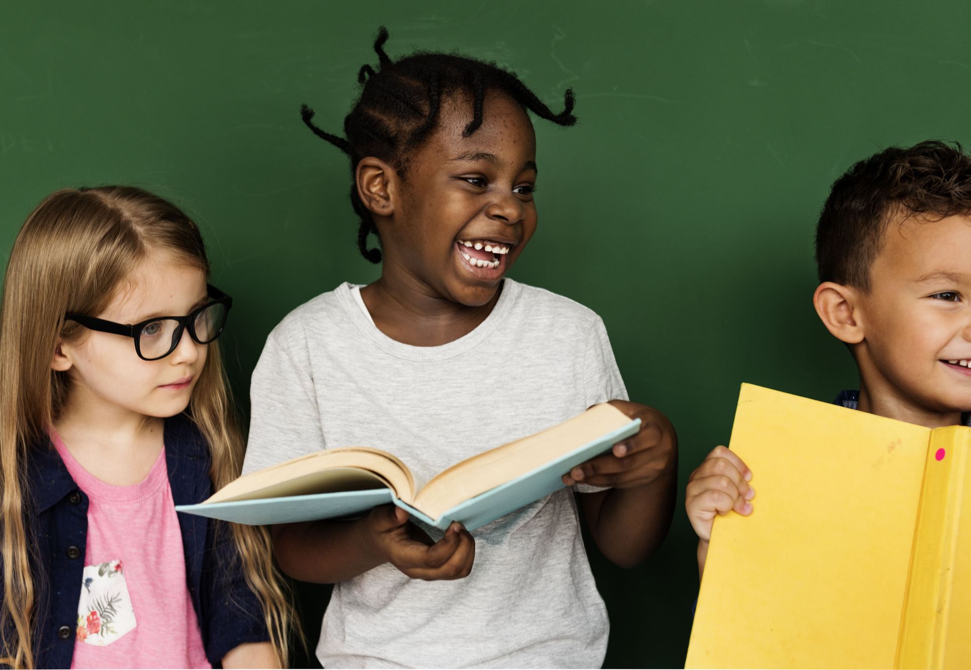A group of children are standing next to each other reading books.