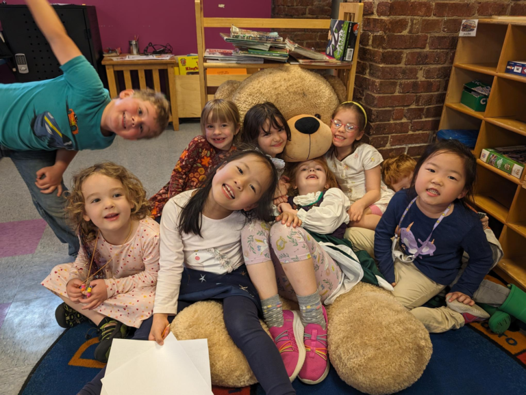 A group of children are posing for a picture with a teddy bear