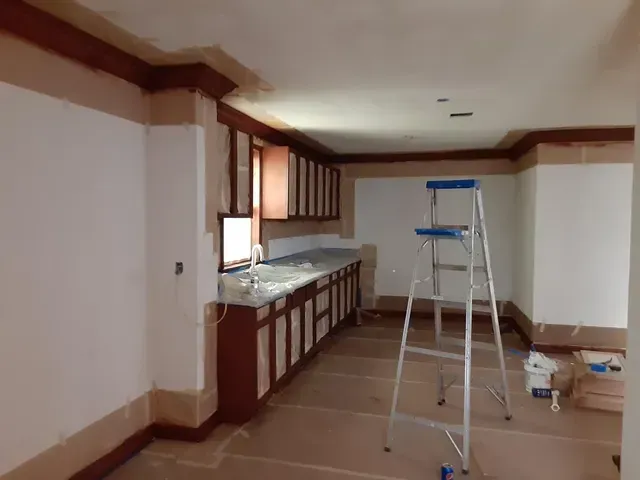 A kitchen with a ladder in the middle of it