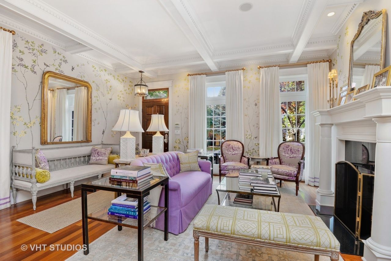 Elegant living room with purple chairs, a sofa, mirrors, and a fireplace by French doors