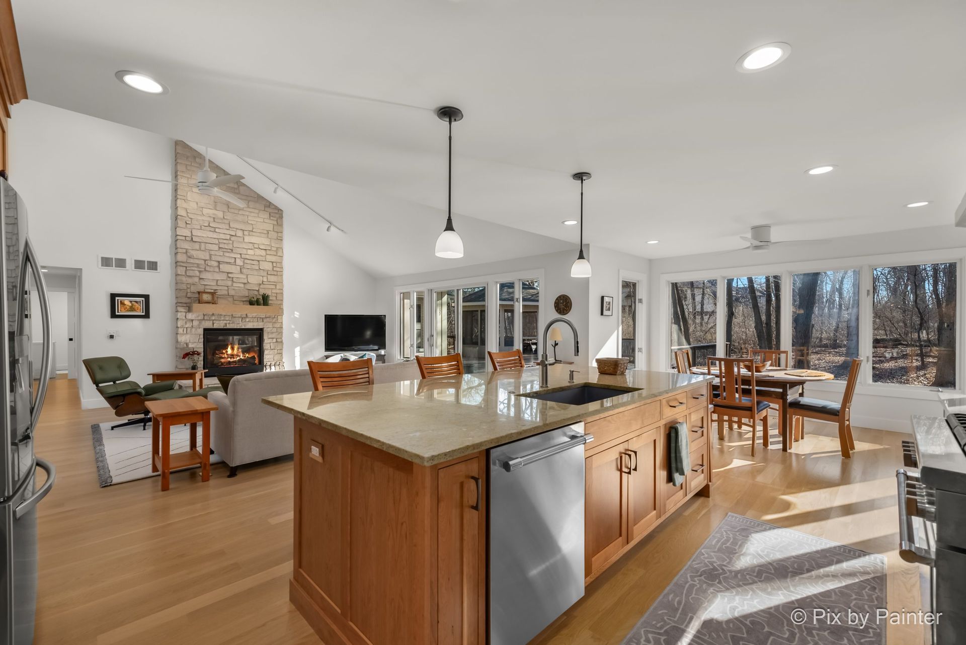 Bright kitchen with a large island, hanging pendant lights, and a bowl of fruit on the counter.