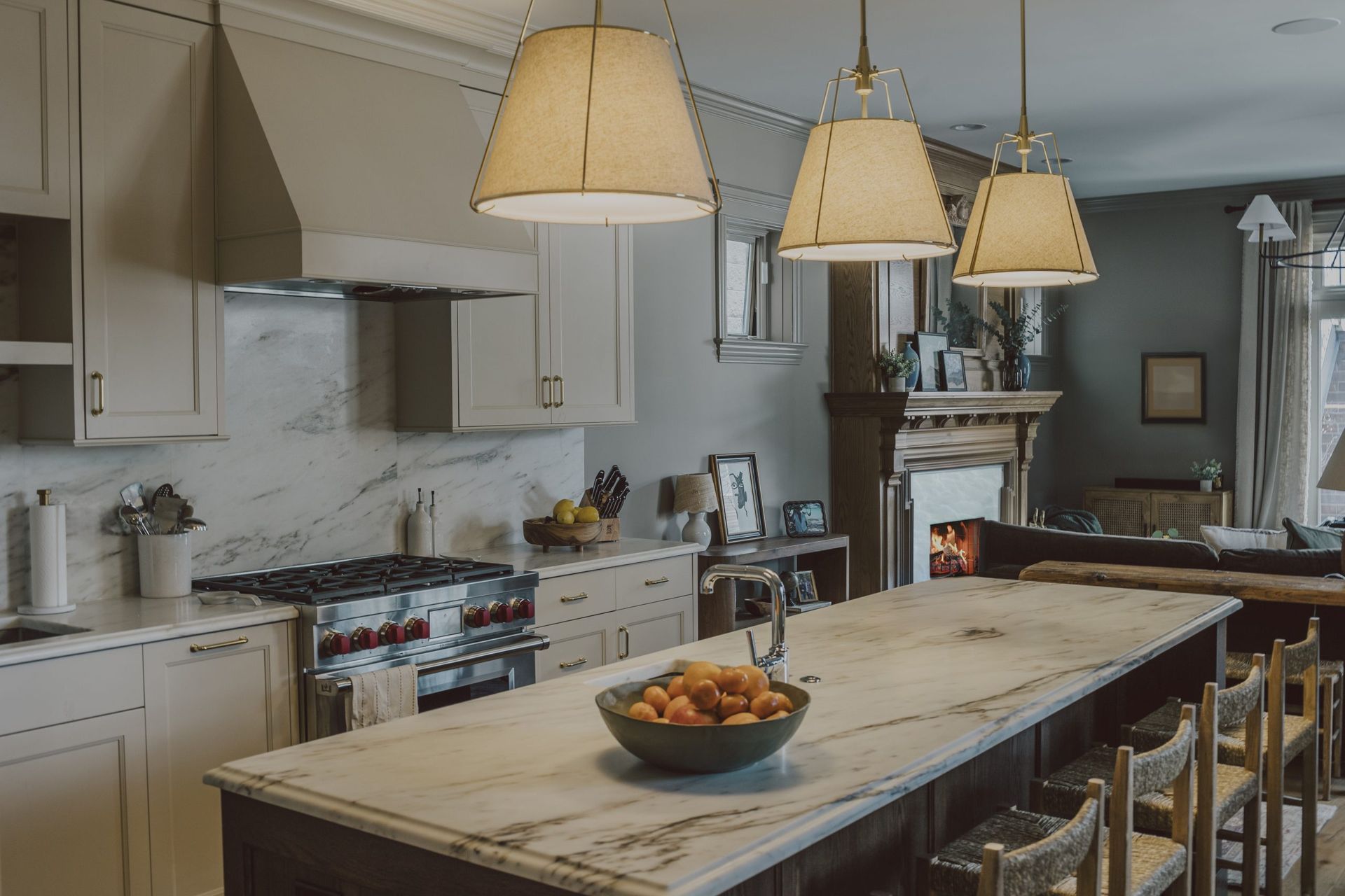Bright kitchen with a large island, hanging pendant lights, and a bowl of fruit on the counter.