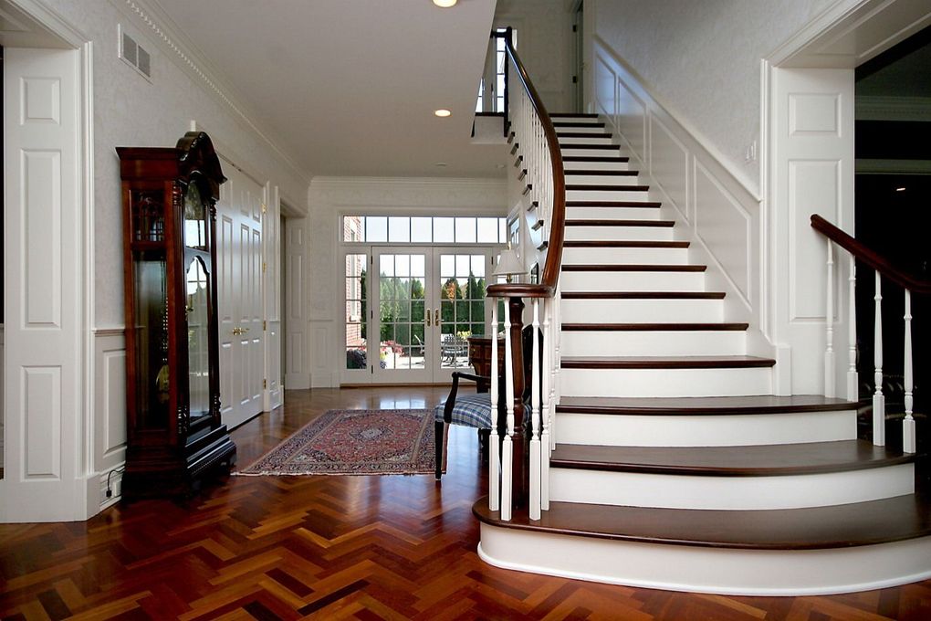 Elegant foyer with white staircase, dark wood floors, and a view of the front entryway