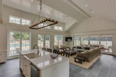 Bright open-concept kitchen and living room with large windows, vaulted ceiling, and modern furnishings