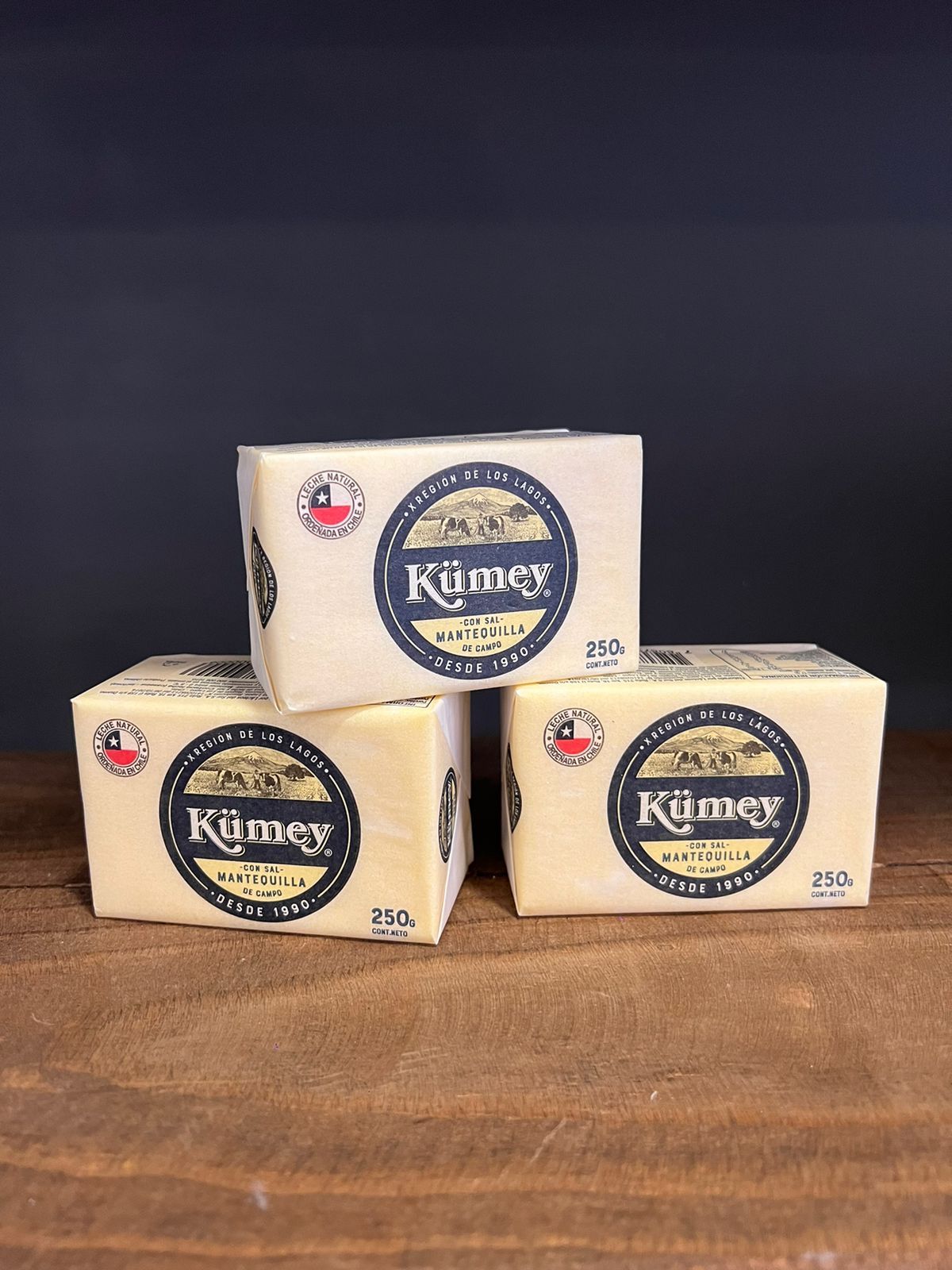 Tres bloques de queso están apilados uno encima del otro sobre una mesa de madera.