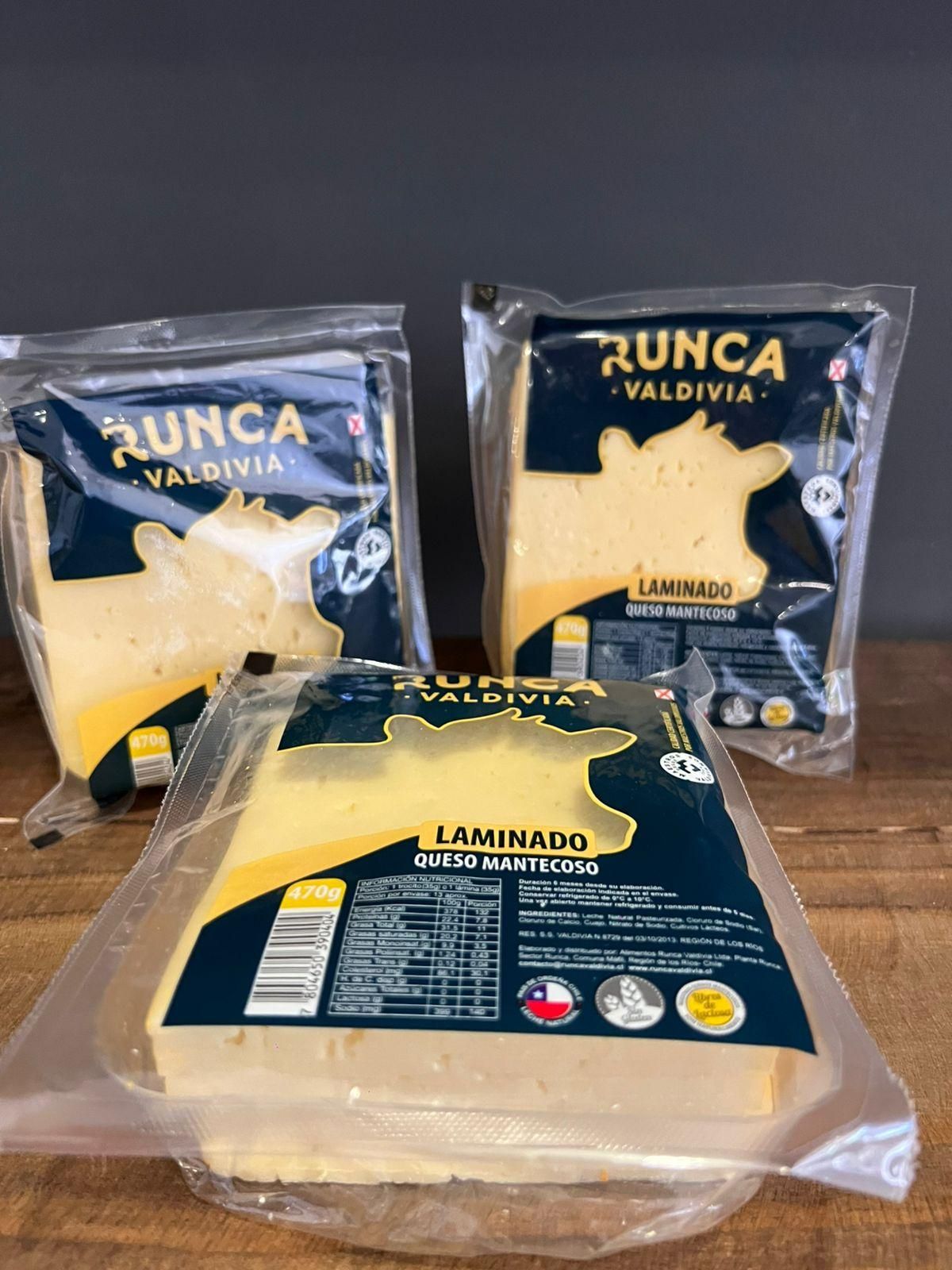 Hay tres bolsas de queso sobre una mesa de madera.