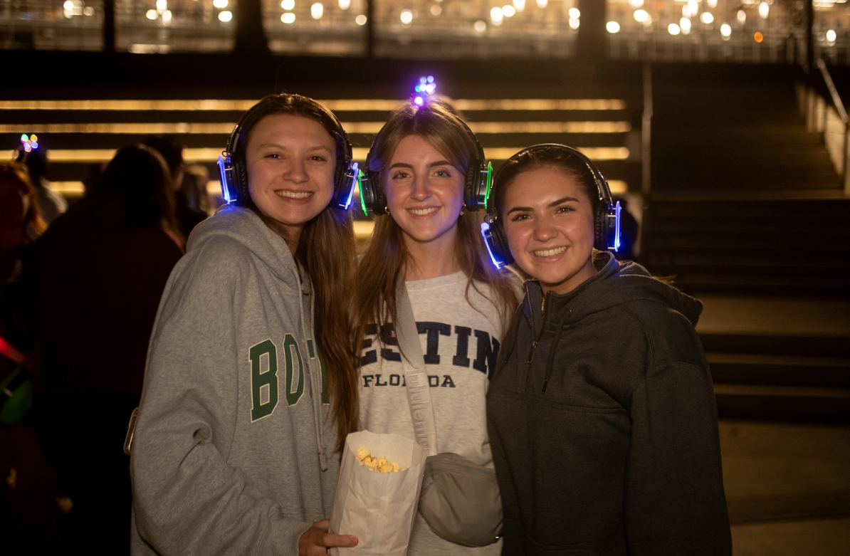 Three women wearing face masks and headphones are posing for a picture.