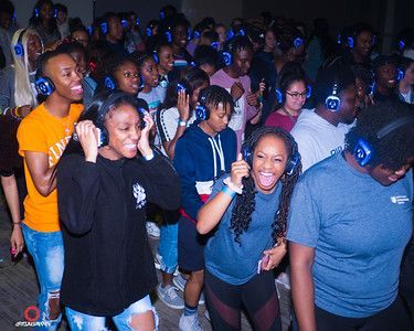 A group of people wearing headphones are dancing at a party.