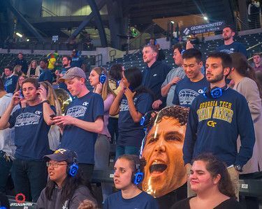 A group of people are sitting in a stadium wearing headphones.