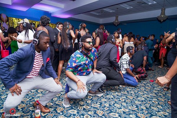 A group of people are dancing in a room with headphones on.