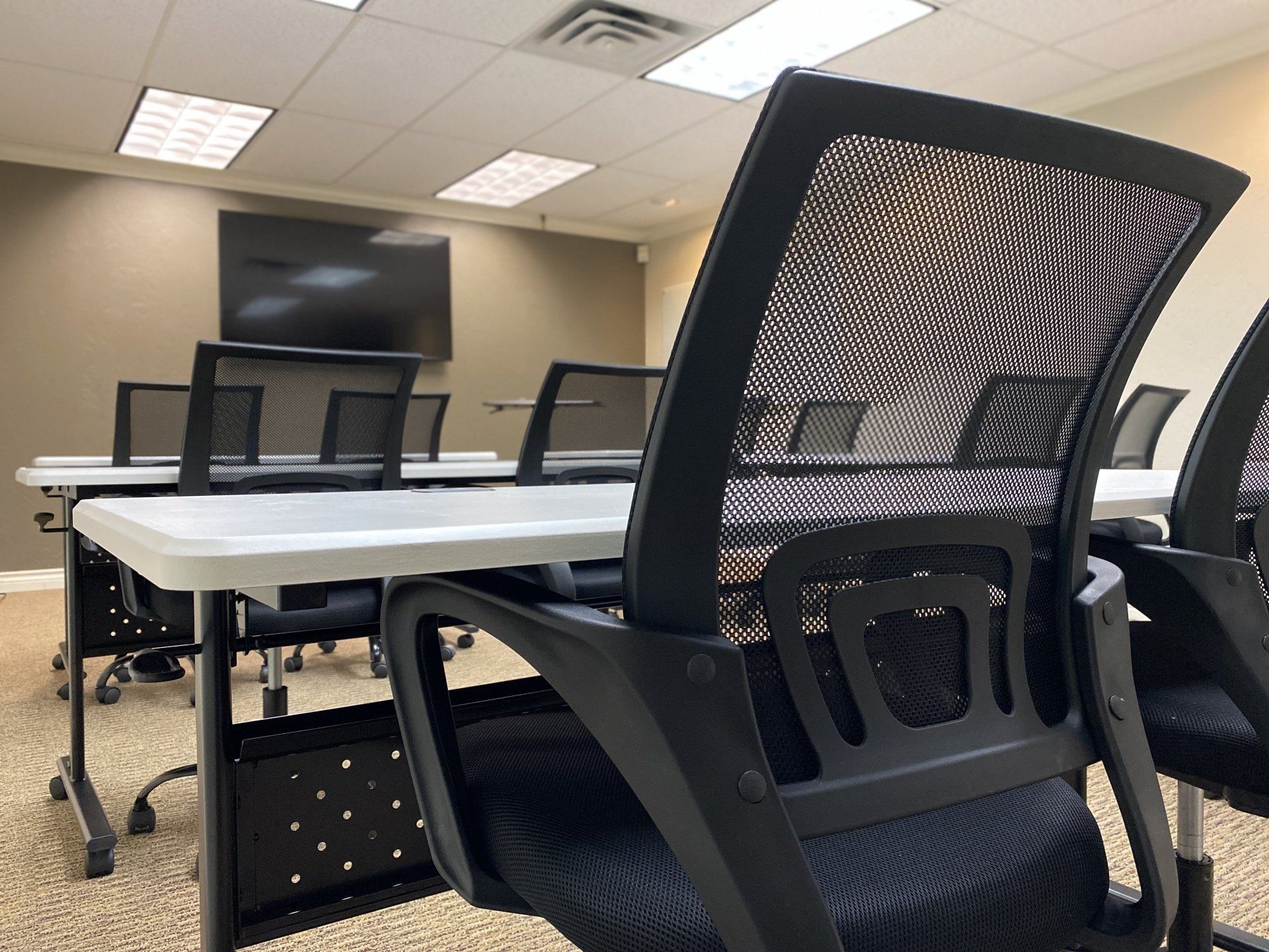 Meeting room with tables, chairs and a tv monitor