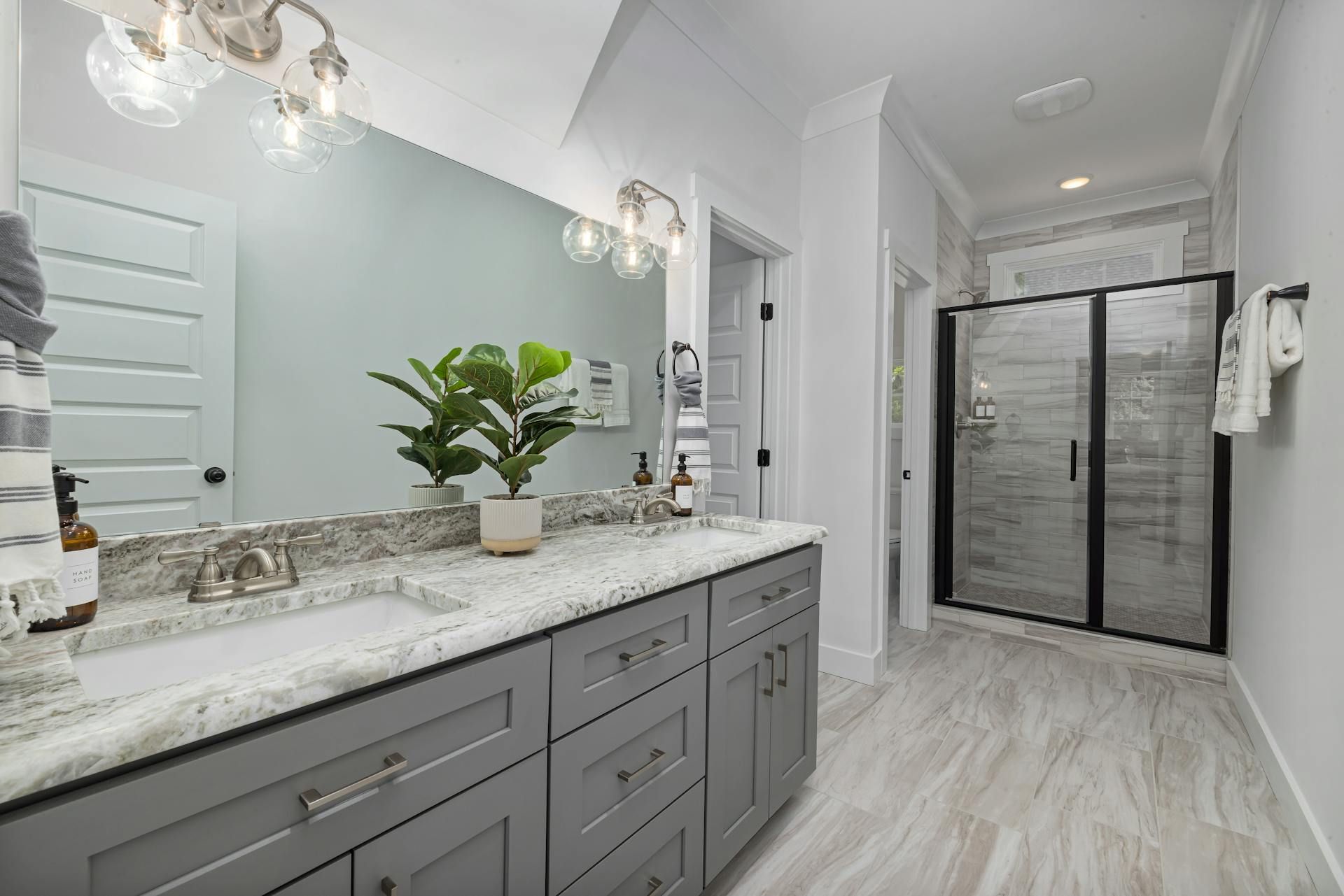 A bathroom with two sinks , a large mirror and a walk in shower.