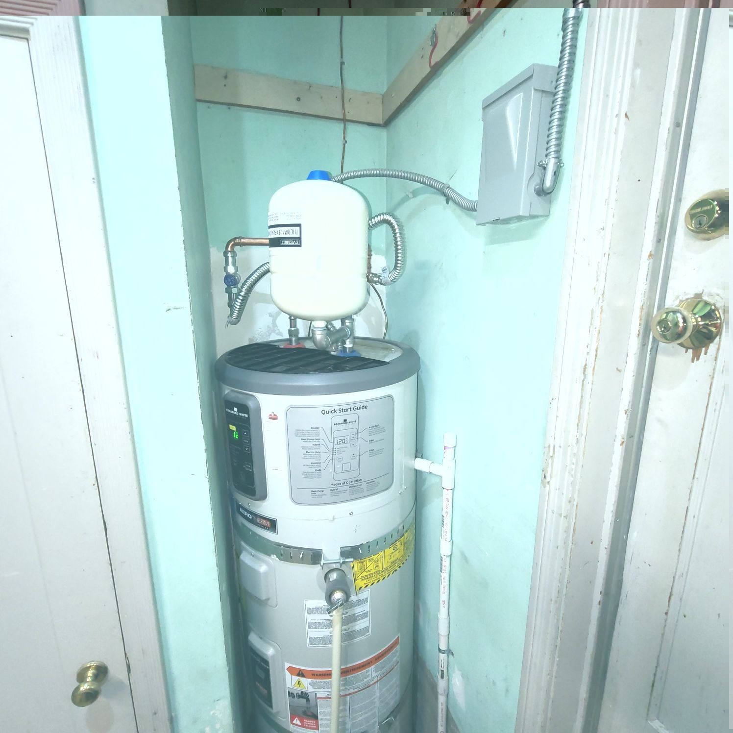 Water heater with expansion tank in a utility closet.